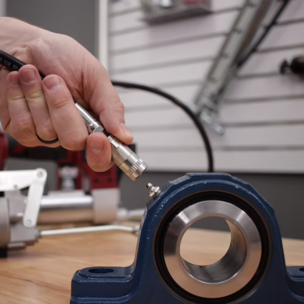 A technician lubricating a pillow block bearing with a grease gun