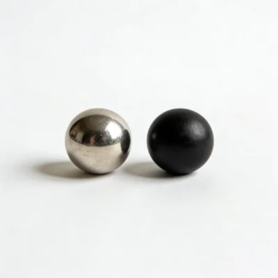 Side-by-side comparison of a steel ball and a black ceramic ball